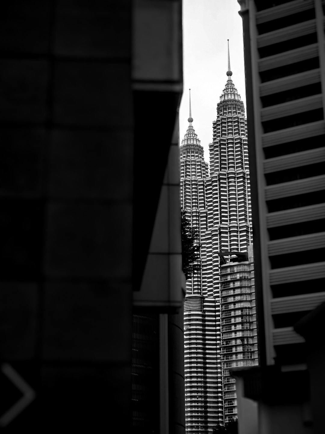 Two spired skyscrapers with tiered facades rise above a city.